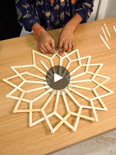 a woman is making a wooden snowflake out of popsicles on a table