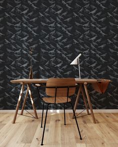 a desk with two chairs and a lamp on it in front of a black wall