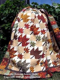 a quilted bag sitting on top of a grass covered ground in front of some bushes