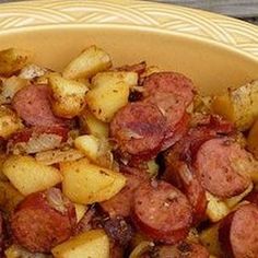 a yellow bowl filled with cooked sausage and potatoes