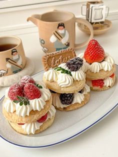 small desserts are arranged on a plate with cups and mugs in the background