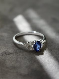 a blue and white diamond ring sitting on top of a gray surface with shadows coming through it