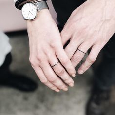 a person wearing a wrist watch and holding their hand out to the side with both hands