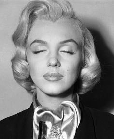 a black and white photo of a woman with her eyes closed wearing a bow tie