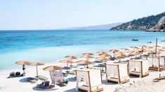 umbrellas and chairs on the beach with clear blue water