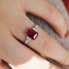 a woman's hand with a ring on it and a red stone in the middle