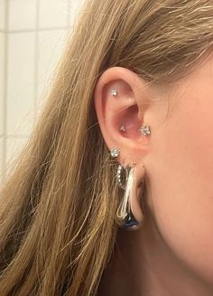 a close up of a person with ear piercings on their ears and in the background is a tiled wall