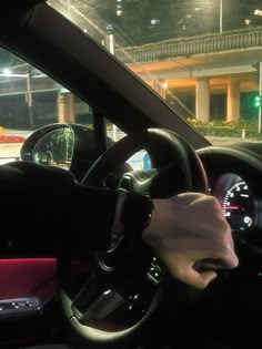 a person driving a car at night with their hand on the steering wheel