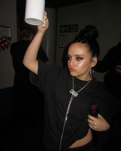 a woman holding up a white cup in the air with her hand on top of it