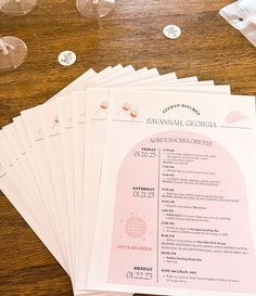 a bunch of papers sitting on top of a wooden table next to wine glasses and silverware