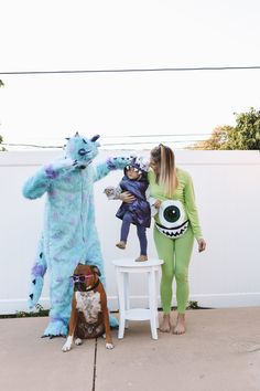 a woman standing next to two dogs and a man in costumes with monsters on them