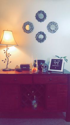 a wooden table topped with a lamp next to a wall mounted clock and other decorations