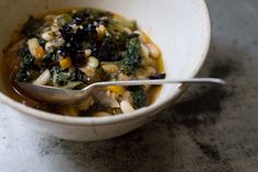 a white bowl filled with soup sitting on top of a table next to a spoon