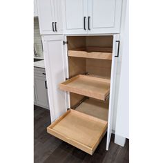 an open cabinet door in a kitchen with white cabinets and wood flooring on the side