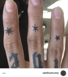 two fingers with tattoos on them and one has a star tattoo on the middle finger