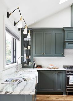 a kitchen with green cabinets and marble counter tops