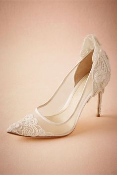 a pair of white high heel shoes with lace on the toes and heels are shown