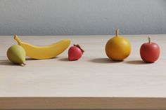 three plastic fruits and two bananas on a table