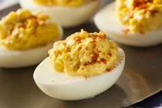 deviled eggs with mustard and seasoning sit on a metal plate, ready to be eaten