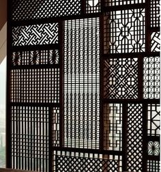 an intricately designed screen in the corner of a room with a window and cityscape behind it