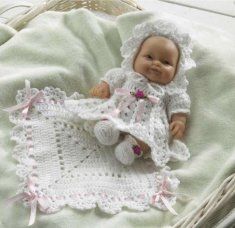 a small baby doll laying on top of a blanket next to a wicker basket