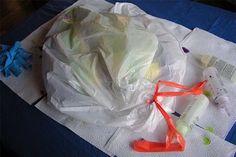 plastic bags, scissors and other items are sitting on a blue tablecloth covered with white paper