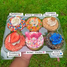 a person holding up a tray with different types of cupcakes