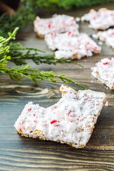 small crackers with candy canes on them sitting on a wooden table next to greenery