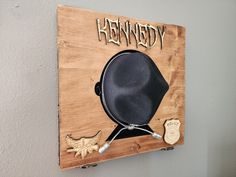 a wooden sign with a black hat on it