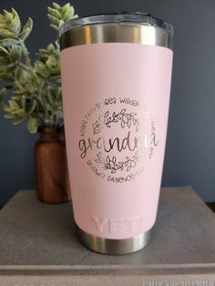 a pink tumbler sitting on top of a counter next to a potted plant