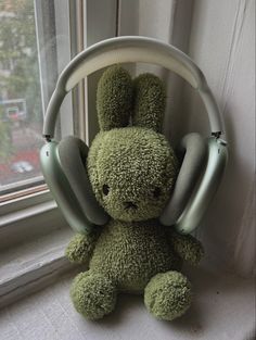 a stuffed animal sitting in front of a window with headphones on it's ears