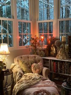 a living room filled with lots of furniture and windows covered in blankets, candles and books