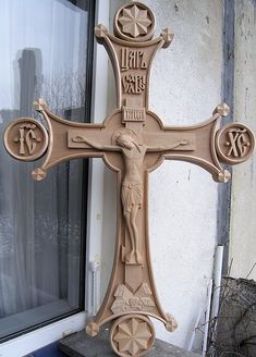 a carved wooden cross sitting in front of a window