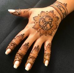 a woman's hand with henna tattoos on it, showing the intricate design