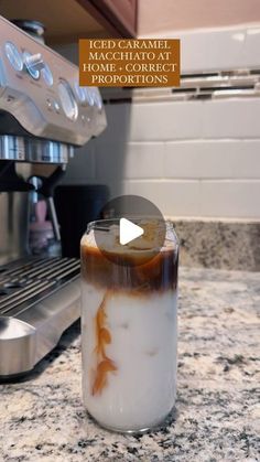 an iced caramel drink in a jar sitting on a kitchen counter next to a coffee maker