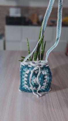 a small crocheted bag sitting on top of a table next to a plant