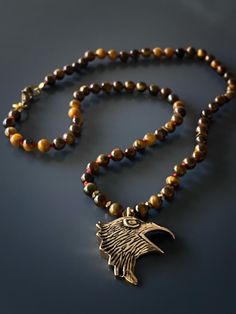 Express your freedom with the Eagle Tiger's Eye Necklace. This necklace is sure to elevate any stylish man's and women's look and the eagle symbolizes your strength and freedom. I combined tiger's eye stone beads with a high quality bronze , handmade and hand engraved Eagle Spirit Necklace represent freedom and power. Tiger's Eye traditionally is carried to protect the person against curses and ill intent. Tiger's eye brings self confidence to the wearer and resonates with both the root and sacr Bronze Spiritual Jewelry With Polished Beads, Tiger Eye Stone Jewelry, Blue Tiger Eye Stone, Tiger Eye Necklace Handmade, Men Tiger Eye Necklace, Tigers Eye Crystal Necklace, Eagle Pendant, Eagle Necklace, Tigers Eye Necklace