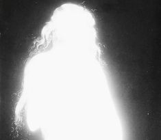 a woman with long curly hair standing in the dark