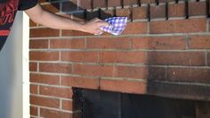 a person is cleaning a brick fireplace with a towel and rag in their left hand