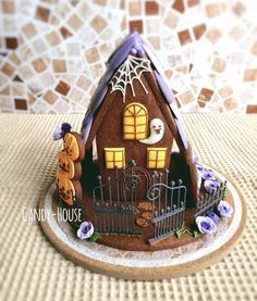 a gingerbread house is decorated with purple and white decorations on the outside, along with blue flowers