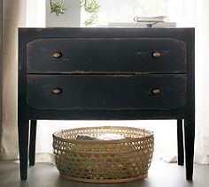 a black dresser with a basket underneath it