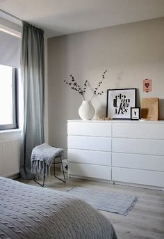 a white dresser sitting next to a window filled with pictures and vase on top of it