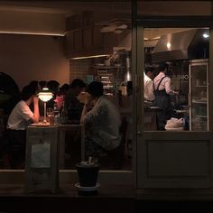 a group of people standing in a kitchen next to each other near a window at night