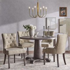 a dining room table with chairs and a chandelier hanging from the ceiling above it