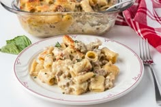 a white plate topped with pasta next to a casserole dish filled with meat