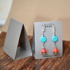 a pair of earrings with coral and turquoise beads on them sitting in front of a box