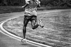 black and white photograph of a person running on a road with trees in the background