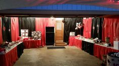 a room with red curtains and black drapes on the walls is set up for an event