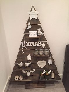 a christmas tree made out of wooden pallets with ornaments on it and the word xmas written in white