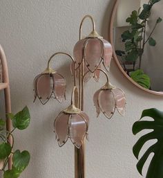 a pink glass flower on a metal stand next to a mirror and potted plant